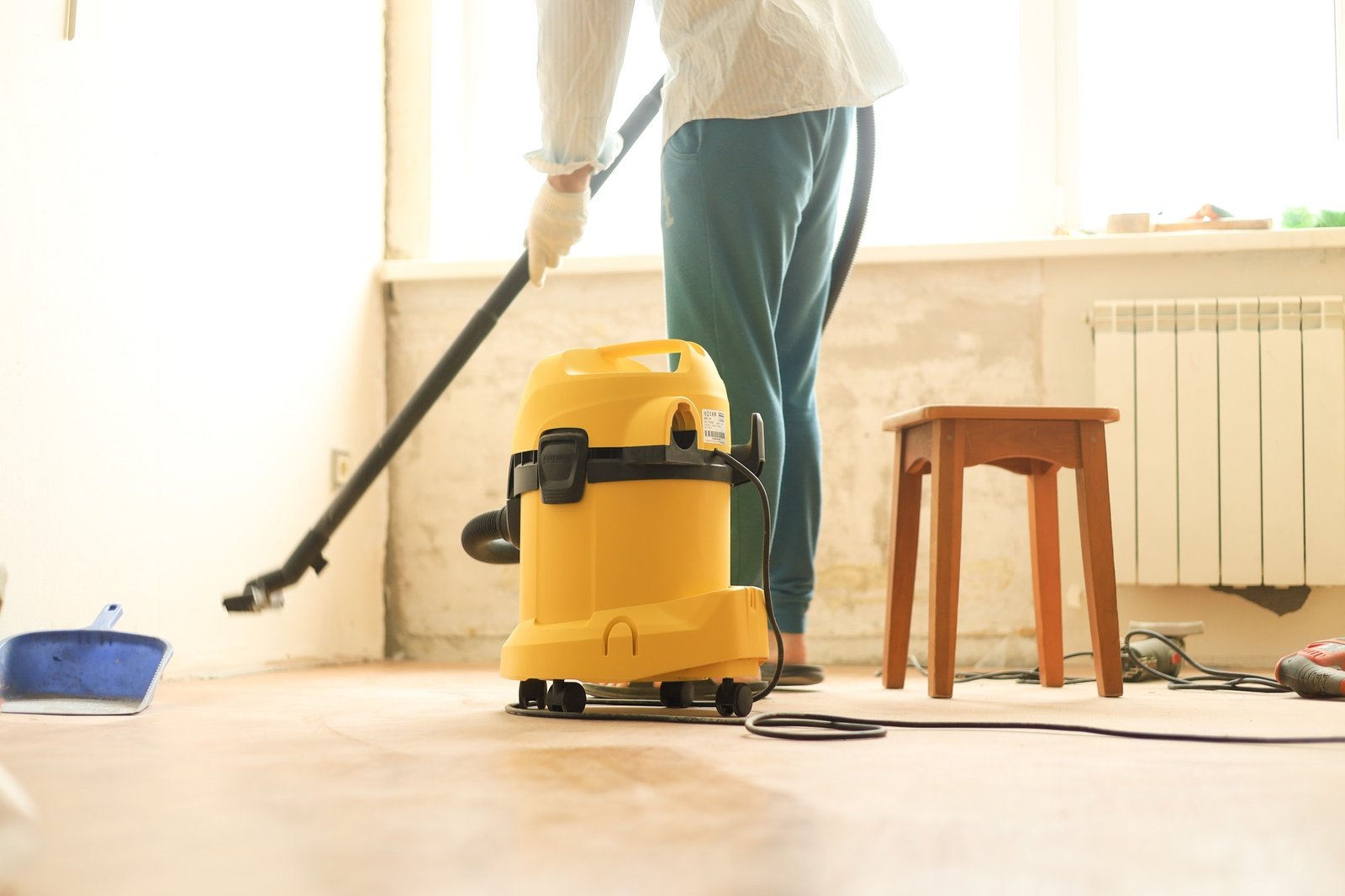 A man is cleaning the room during repairs using a construction vacuum cleaner