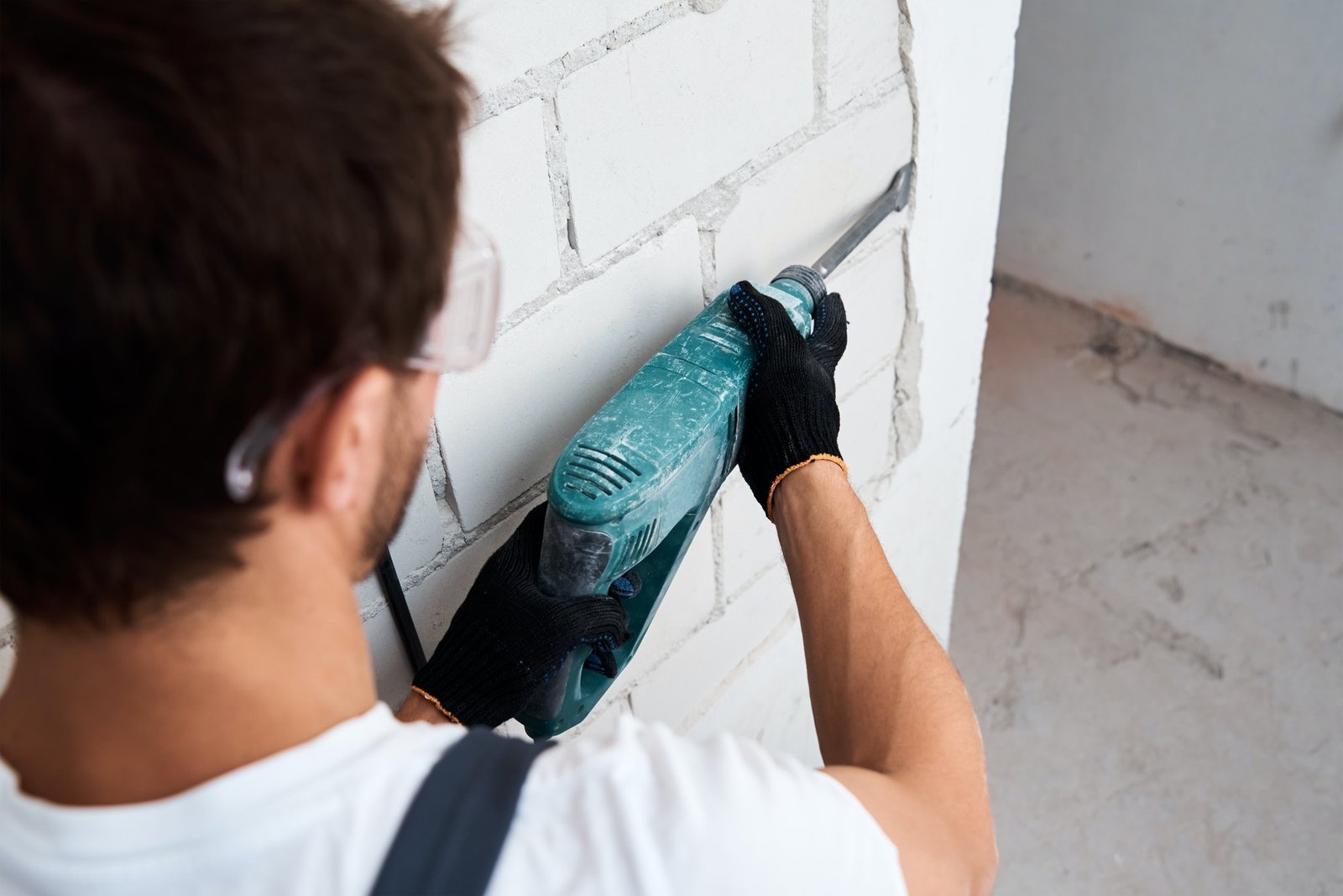 Man with demolition hammer remove stucco from wall. Renovation concept